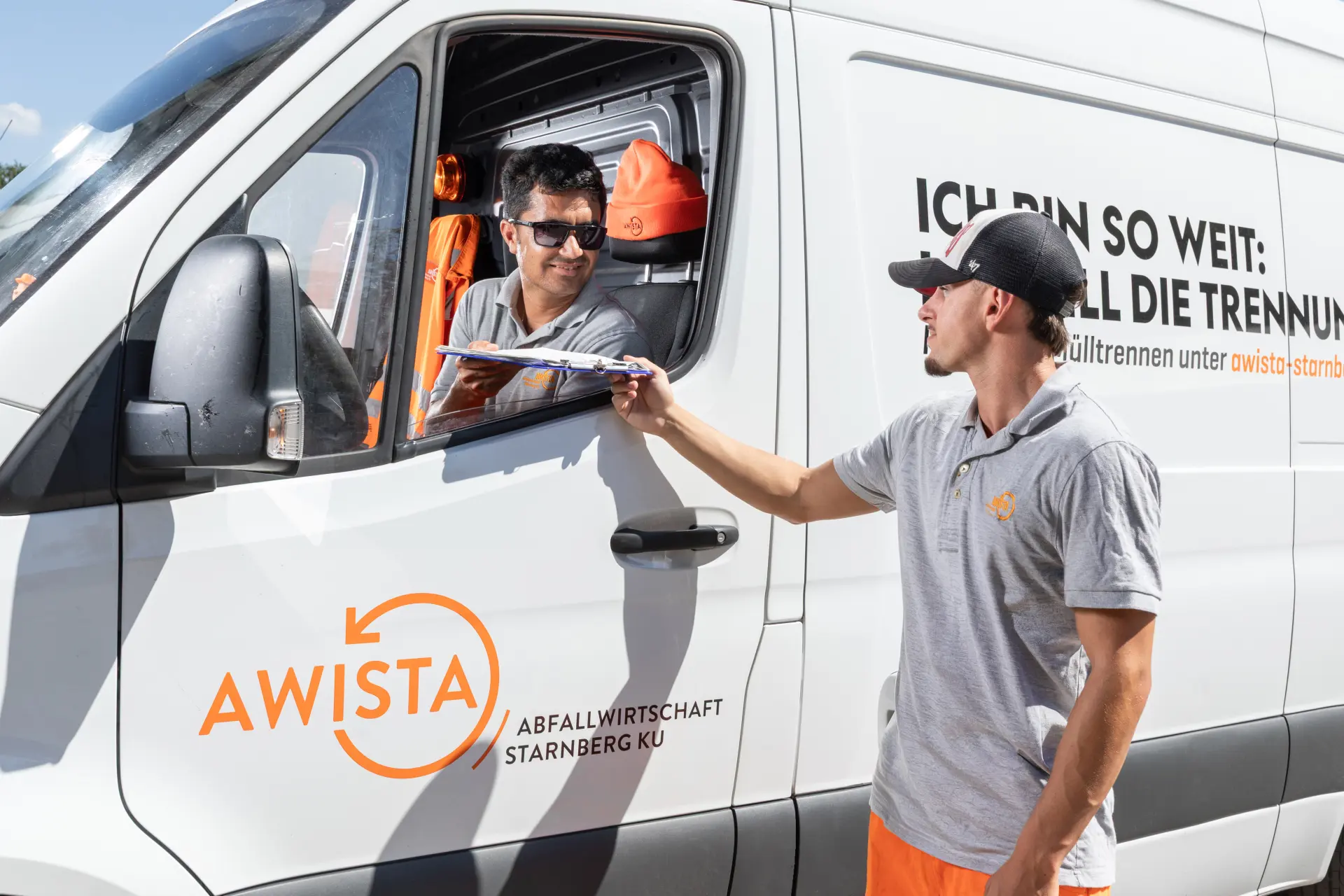 Service-Mitarbeiter sitzt im Sprinter und gibt ein Klemmbrett an einen zweiten Service-Mitarbeiter