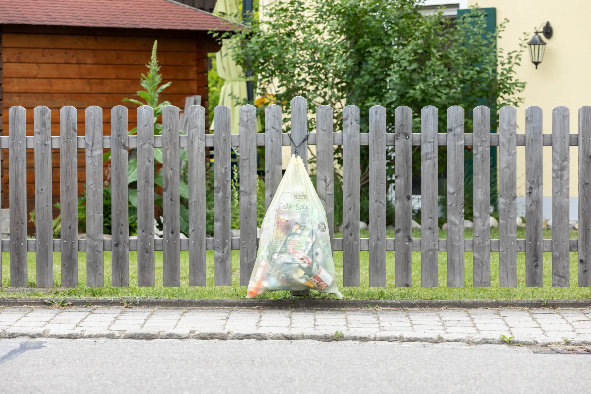 Gelber Sack hängt am Gartenzaun