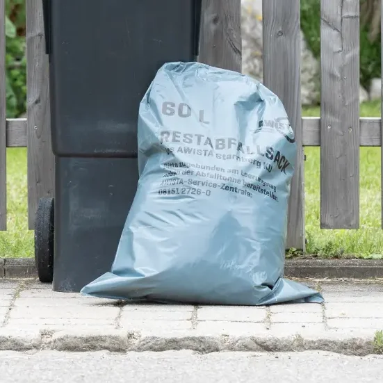 Restmülltonnen und Restmüllsack vor Gartenzaun