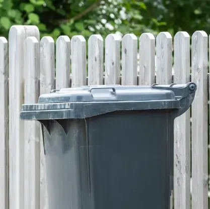 Restmülltonne vor Gartenzaun