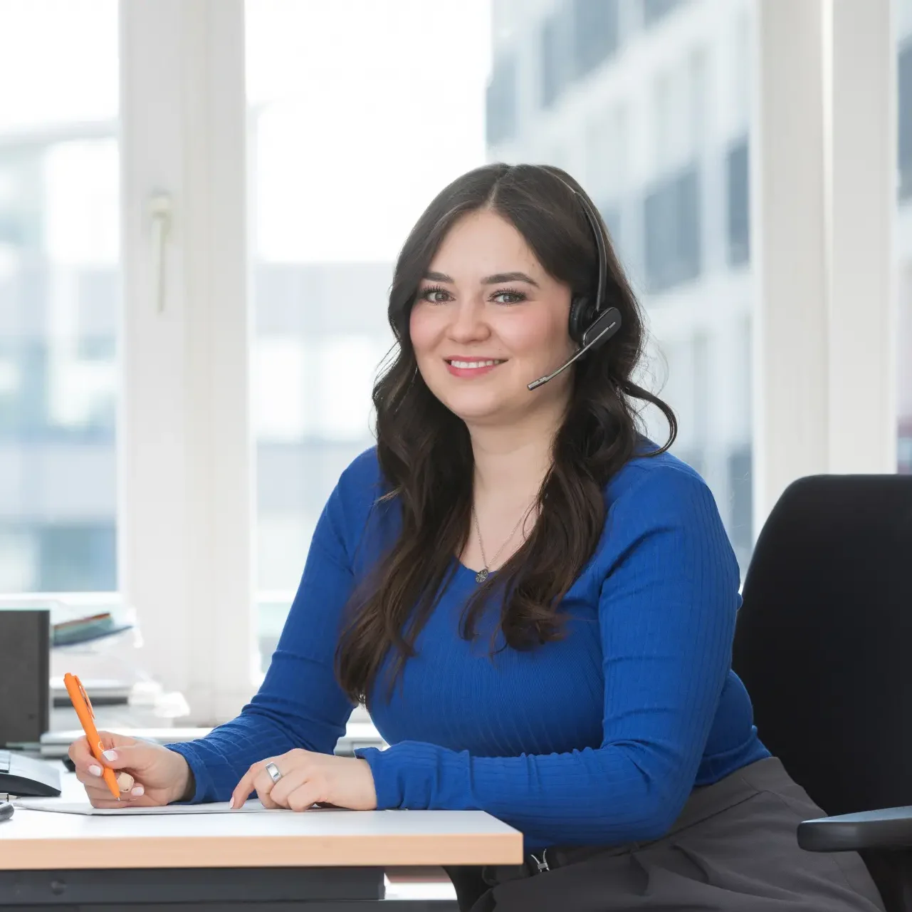 Frau mit Headset am Schreibtisch